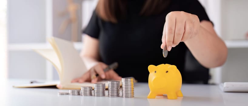 Woman hand putting coins in a piggy bank for save money and saving money concept.