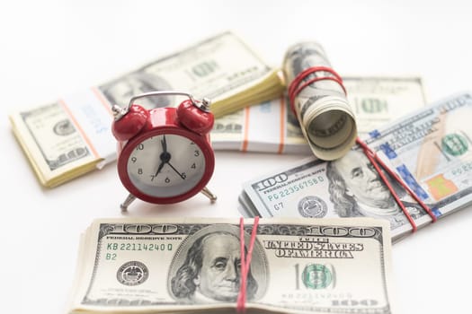 One dollar bills on a wooden table with a red alarm clock in the composition. Money saving concept. . High quality photo