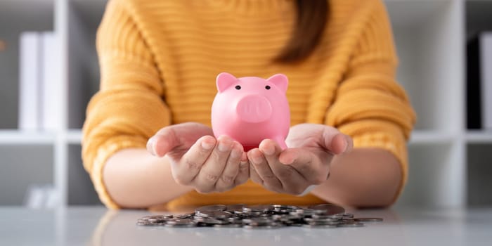A woman is holding a piggy bank in his hands for a money or finance concept, support saving bank, Protect saving money concept.
