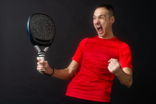 Smiling man with racket and paddle ball dressed in sport clothes isolated background. Front view. High quality photo