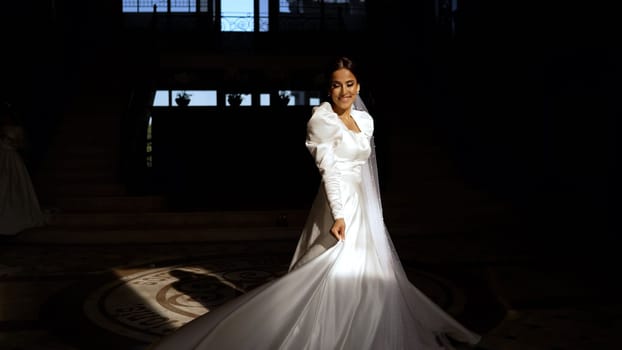 Beautiful young bride in a white dress in a dark interior. A frantic young bride in a dark corridor.