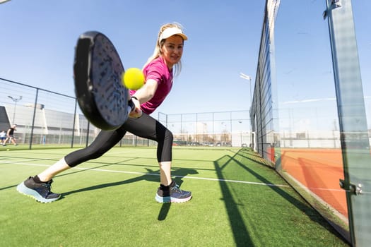 Sportive young girl with racquet playing padel in the open court outdoors. High quality photo
