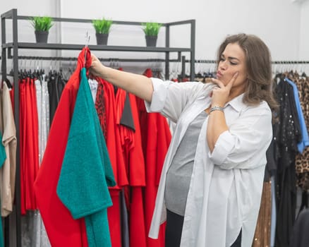 A fat woman chooses clothes in a plus size store