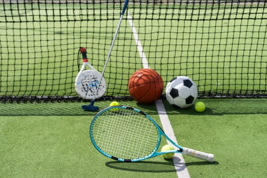 football soccer ball basketball tennis ball and racket laid on grass at sunset. High quality photo