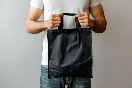 A man is holding black tote bag canvas fabric for mockup blank template, Empty reusable tote bag mockup.