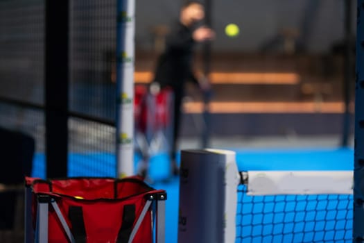 Twoo balls next to the net of a blue paddle tennis court. Sport healthy concept. High quality photo