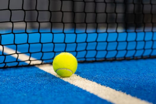 several balls by the net on a blue paddle tennis court. High quality photo