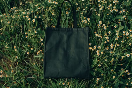 Mockup of a black tote bag laying on grass, Black cotton or mesh eco bag on green grass..