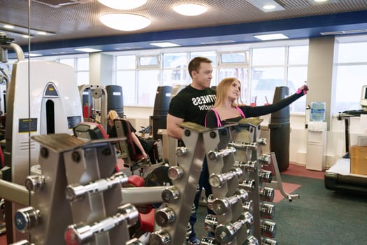 At gym. Cute girl doing selfie with her fitness instructor