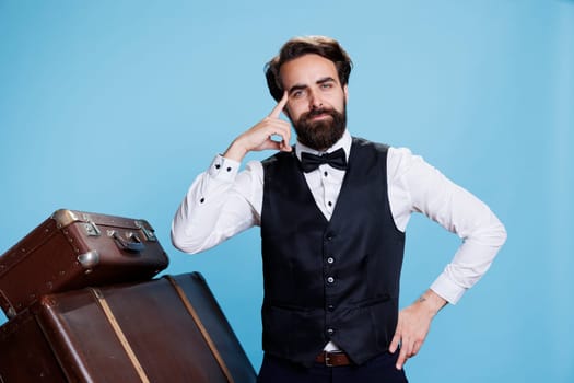 Hotel concierge being pensive on camera, thinking about new ideas to provide excellent service to guests. Man bellhop taking care of luggage, acting thoughtful or contemplative in studio.