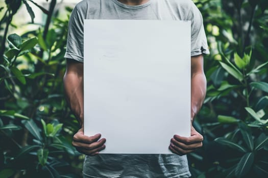 A man holding a white sheet of paper in front of his face, obscuring his features. mockup