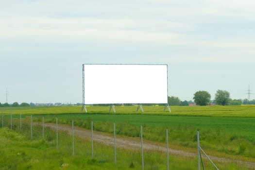 A bare billboard stands alone in the center of a vast field, devoid of any advertisements or messages.