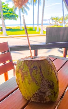 Tropical coconut with straw on the table in Zicatela Puerto Escondido Oaxaca Mexico.