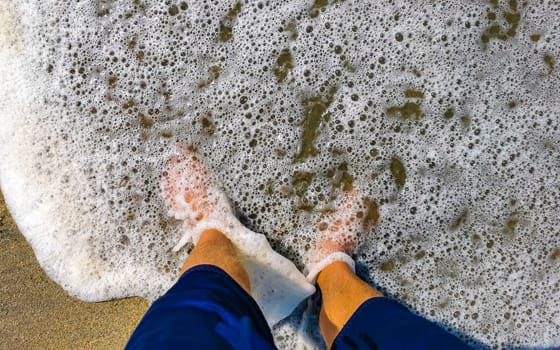 Walking barefoot on the beach sand by the water in Zicatela Puerto Escondido Oaxaca Mexico.