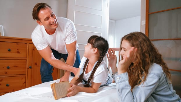 Bedtime story with childhood storytelling, mom and dad reading a fantasy book together to their little young girl in cozy and comfortable bedroom. Modern family happy time. Synchronos
