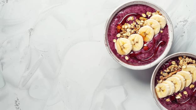 Two bowls of superfood smoothie with bananas, granola crumble, and fresh fruit on a table AIG50