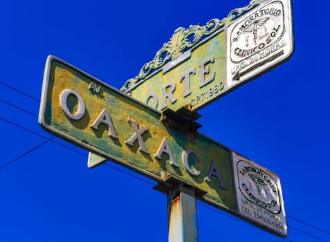 Yellow orange and white road street signs and name for orientation of streets and roads with blue sky in Zicatela Puerto Escondido Oaxaca Mexico.