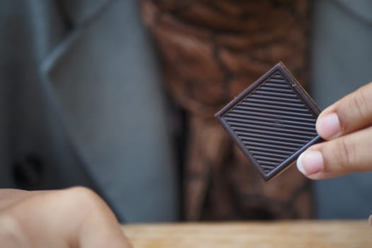 woman holding a dark chocolate candy .