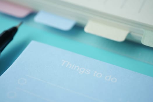 To do list in notebook with office suppliers on desk