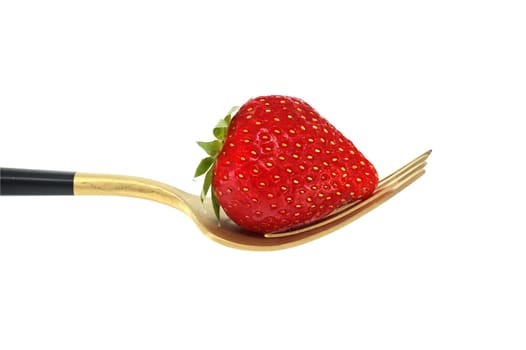 Red strawberry arranged on gold fork with a black handle, set against a white background, symbolizing a concept of healthy diet and organic food