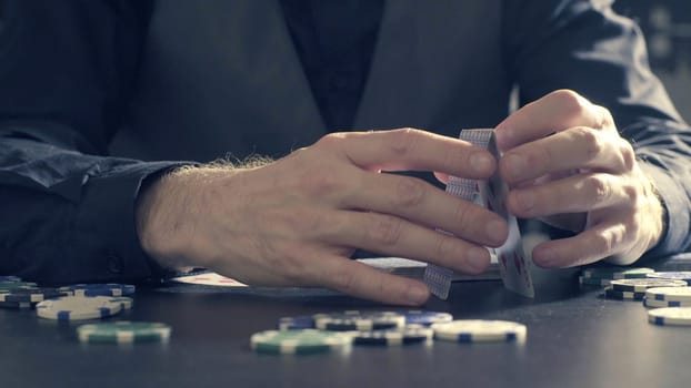 Man's hands building a house of a playing cards. Close up