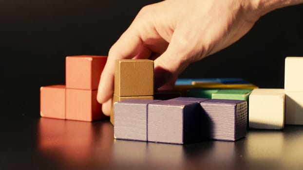 Man's hand picking colored cubes close up. 3D tetris