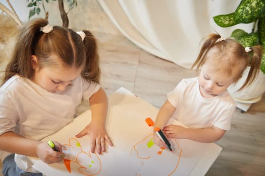 Cute little sisters are painting on table. Preschooler, 4 and 8 years child in living room. Small girl kids doing homework, home schooling concept