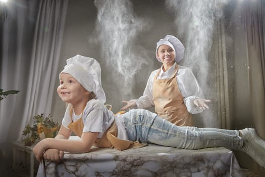Cute oriental family with mother, daughter cooking in the kitchen on Ramadan, Kurban-Bairam. Funny family at a cook photo shoot with flour. Easter