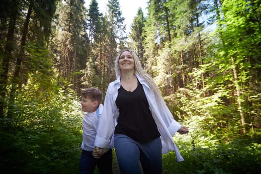 Funny mother with dreadlocks and fat boy happy walking in the forest on a sunny summer day