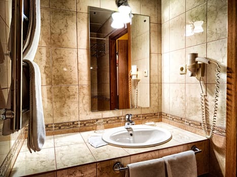 Modern bathroom interior with sink and mirror. Elegant marble bathroom featuring a sink and lit wall mirror