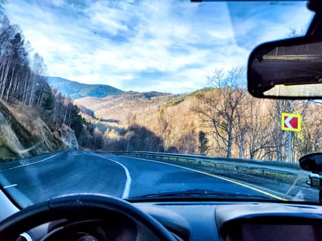 Car salon, windshield, hand of woman on steering wheel and landscape. View from seat of driver on nature landscape. Single trip of female traveler