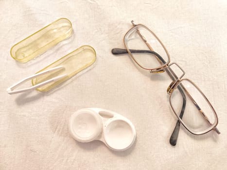 Set for contact lenses with a container, forceps, glasses. The concept of correcting myopia. Contact lens care, cleaning, health. Background, copy space