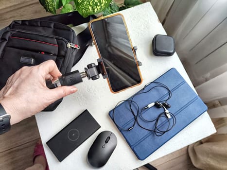 A set of useful blogger devices and hand of female blogger. A neatly organized desk featuring a smartphone, earphones, and various tech gadgets