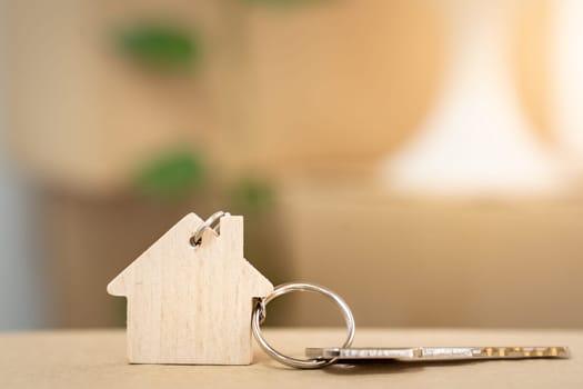 House keys on keyring in the shape of a wooden house with copy-space for text. High quality photo