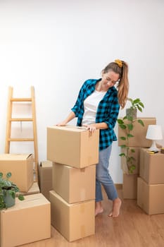 Young attractive woman happy packing cardboard boxes moving in a new home. New house keys, new life. Real estate. High quality photo