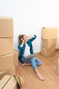 Happy woman sitting on the floor with many boxes, listening music with headphones in a new house - Caucasian girl - High quality photo