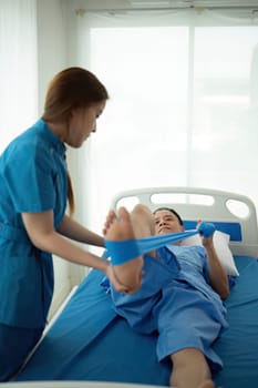 a woman in a blue uniform helps a man in a hospital bed.