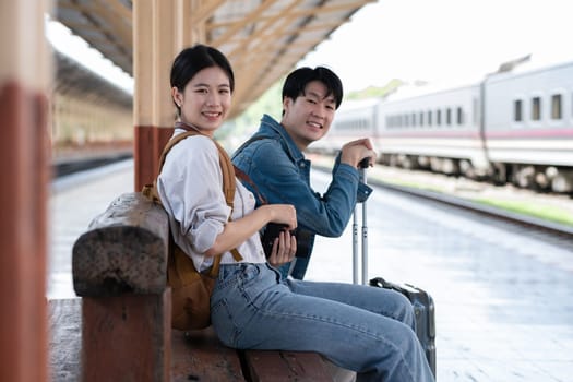 A young Asian couple waits for their train together at the train station, waiting to travel..