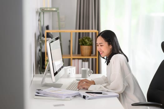 Young businesswoman typing on computer keyboard answering business email in the morning.