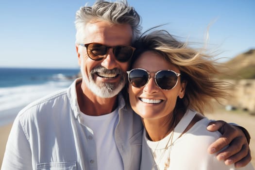 Summer portrait of happy smiling mature couple standing together on sunny coast, woman and man enjoying beach vacation at sea