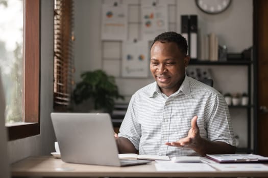 African American businessman working with laptop, online meeting and presenting results via Zoom online..