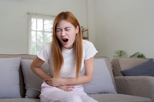 Asian woman having painful from stomach ache at home, Female suffering with abdominal pain.