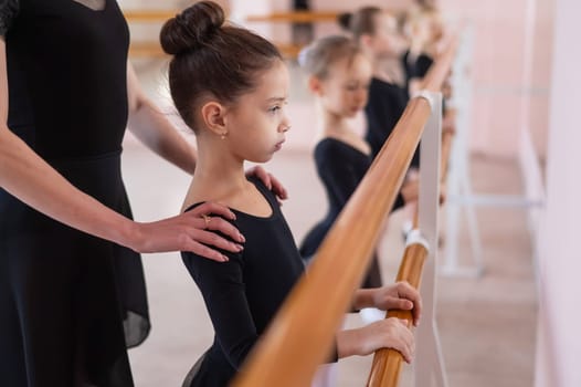 Caucasian woman teaches little girls ballet at the barre