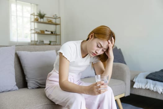 Unhappy sick young asian woman suffer from terrible head pain. touching her head while suffering from a migraine.