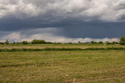Dark storm clouds looming over serene farmland, creating a dramatic rural scene.