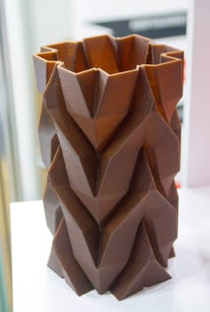 Art object vase printed on 3D printer from melted brown plastic with addition waste coffee. Model made of plastic with spent coffee by 3d printer. Additive progressive technology 3D printing recycling