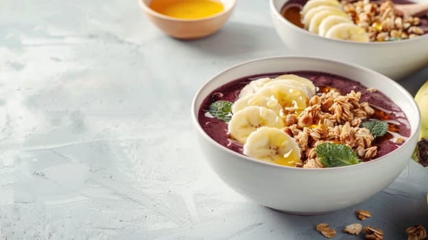 Two bowls of superfood smoothie with bananas, granola crumble, and fresh fruit on a table AIG50