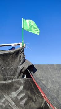 green flag over black Bedouin tent, sky. High quality photo