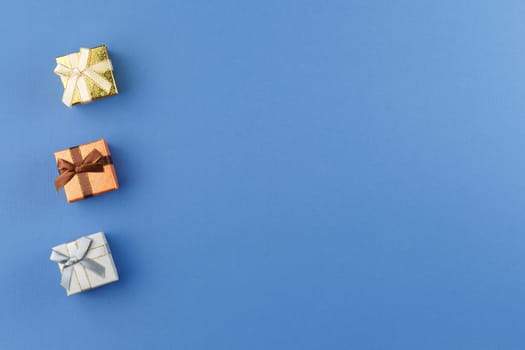 Presents in colorful wrapping paper with ribbon bows on blue isolated background. Flat lay. Festive gift concept. Top view.