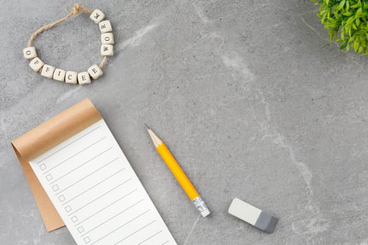 Open notepad, pencil and potted plant on gray marble background. Top view. Office desk concept.